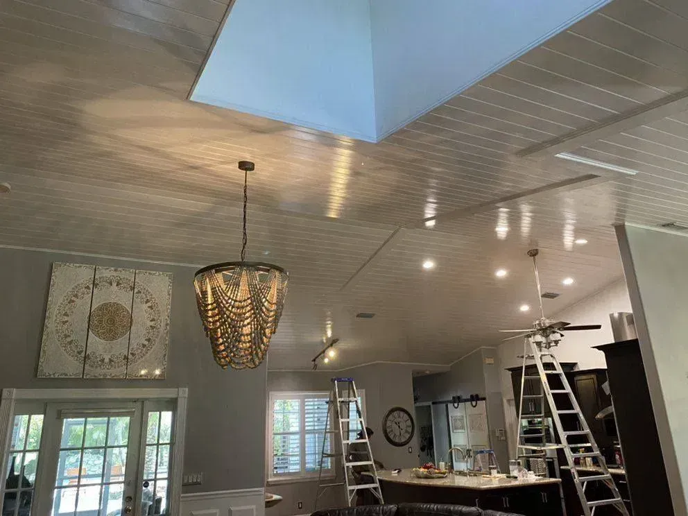 Living room ceiling with lights, chandelier, skylights, and ladders during renovation