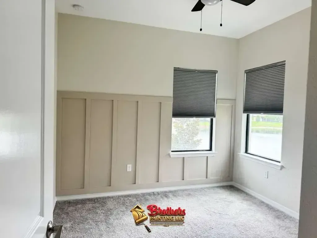 Empty beige bedroom with gray carpet, window blinds, and a ceiling fan.