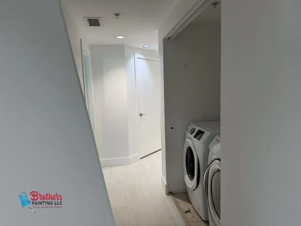 Laundry hallway with a washer and dryer beside a curved white corridor.