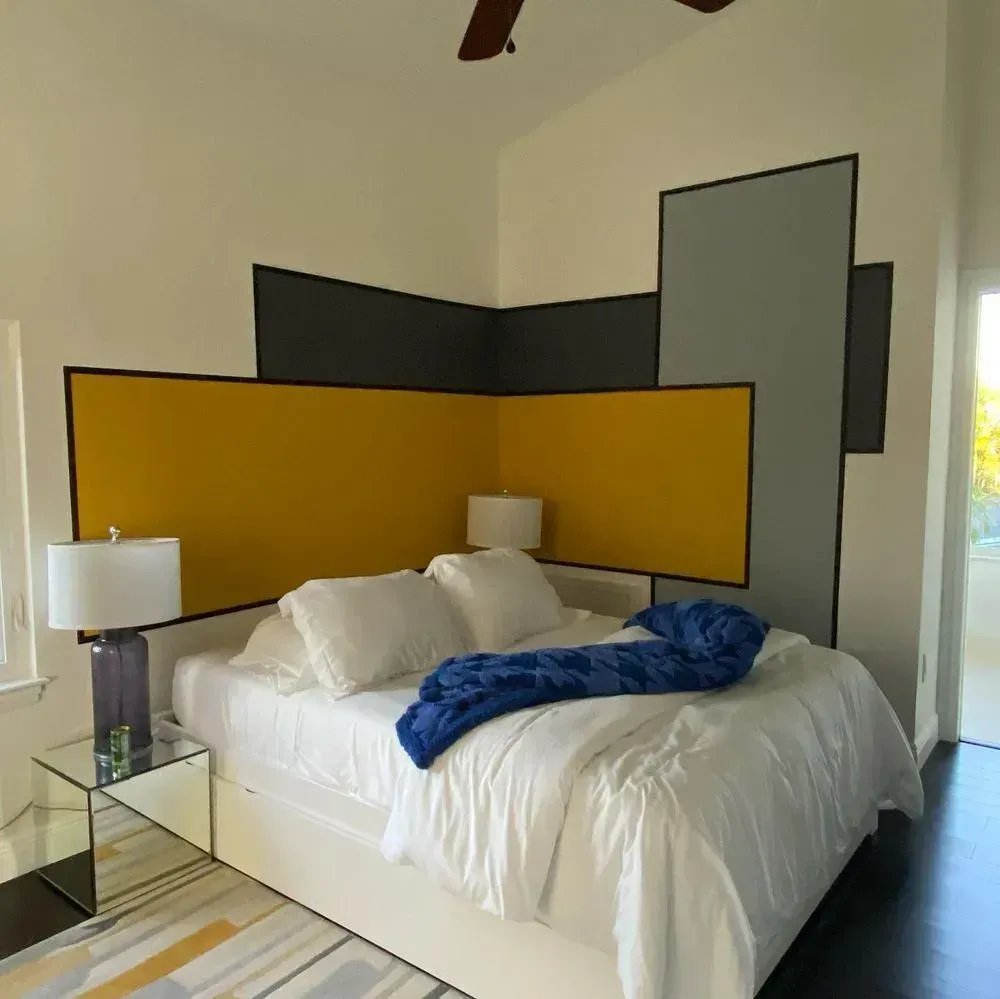 Modern bedroom with white bed, colorful geometric wall panels, and bedside lamps