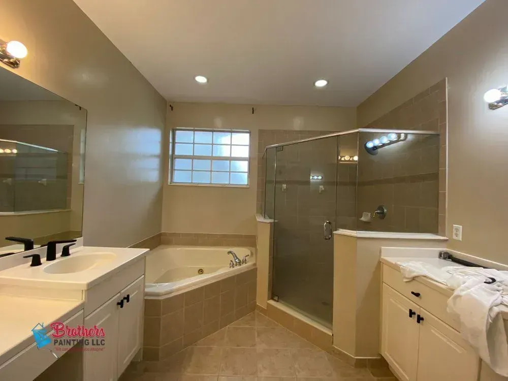 Accessible bathroom with walk-in tub, glass shower, vanity, and beige walls