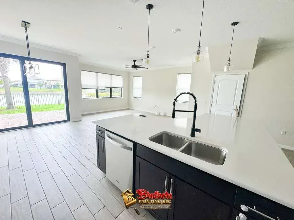 Bright modern kitchen with white island, black cabinets, and large sliding glass doors to a patio.
