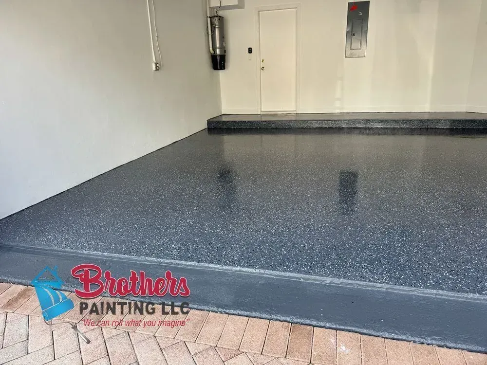 Freshly painted gray garage floor with speckled finish and Brothers Painting LLC logo watermark