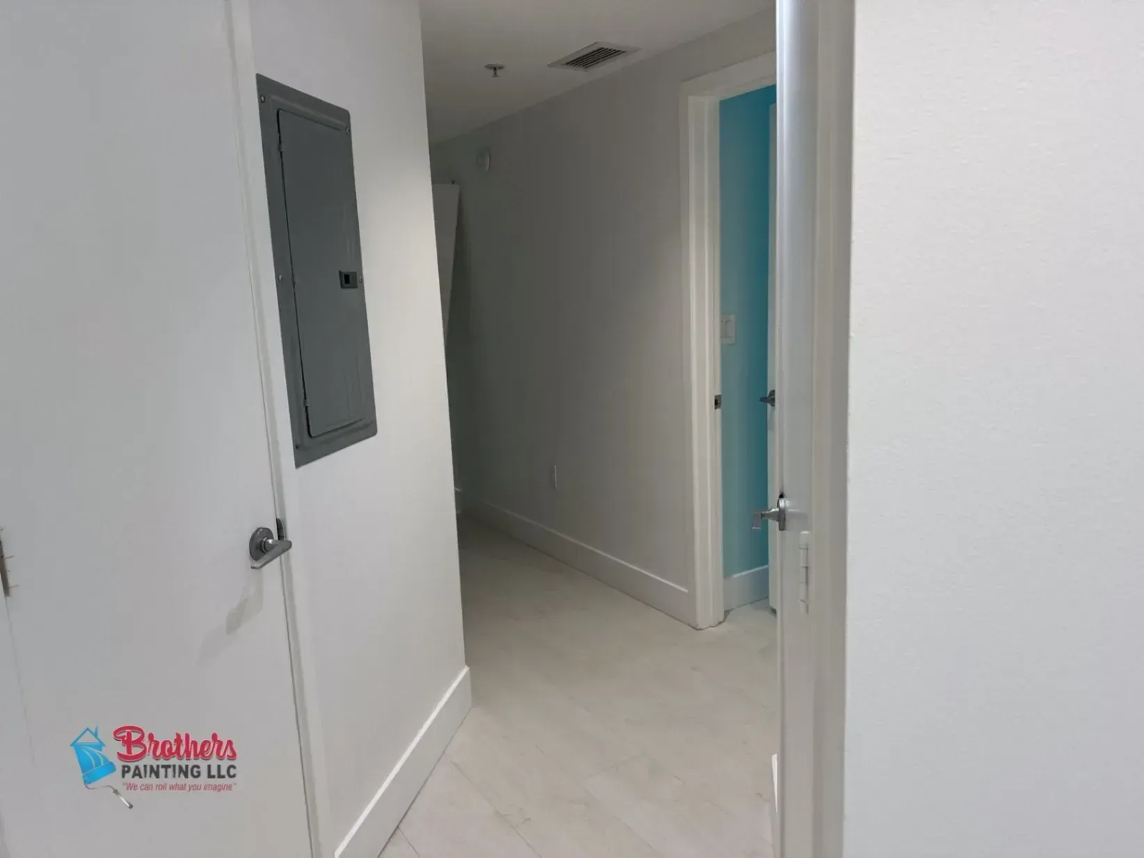 Empty white hallway with open doors and a gray electrical panel on the wall