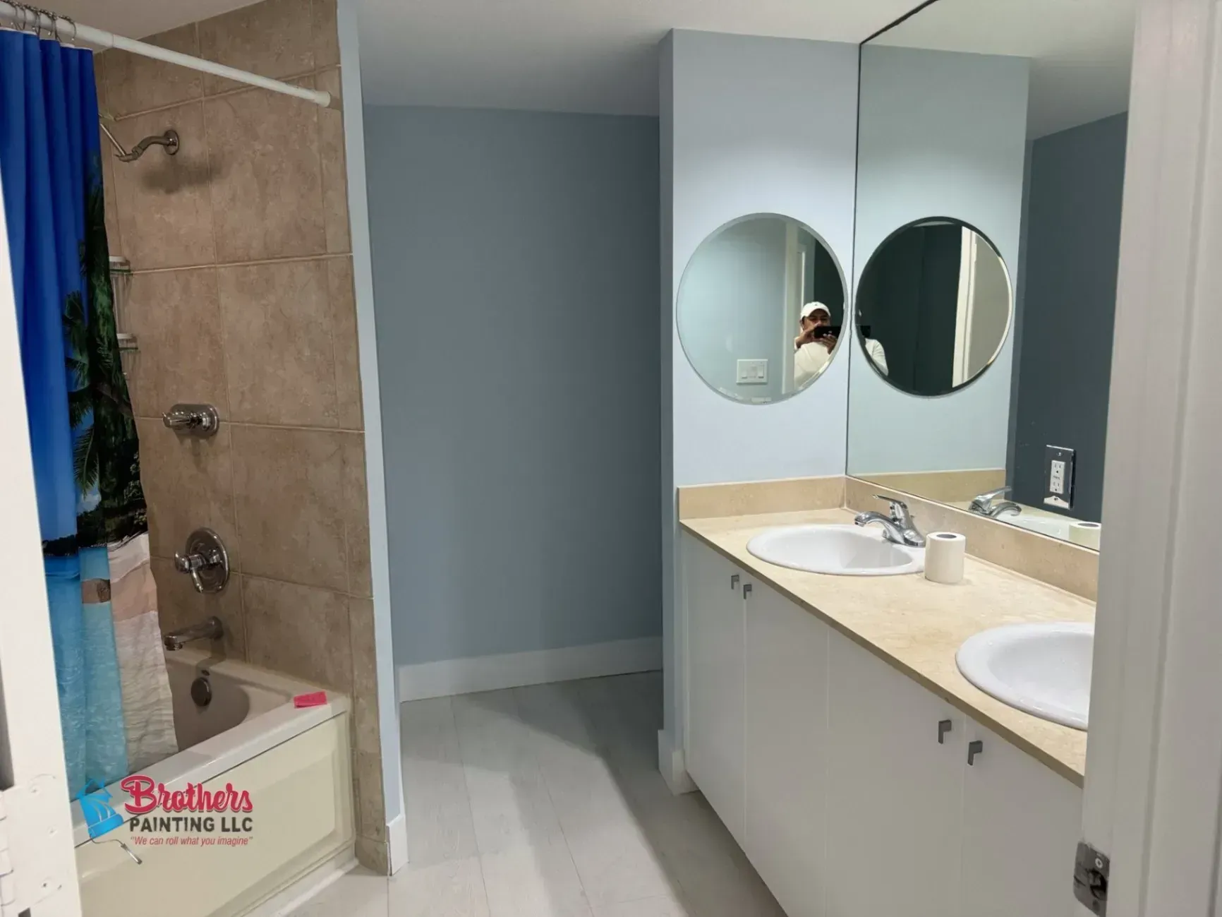 Bathroom with shower stall, double vanity, and round mirrors in light gray and beige tones