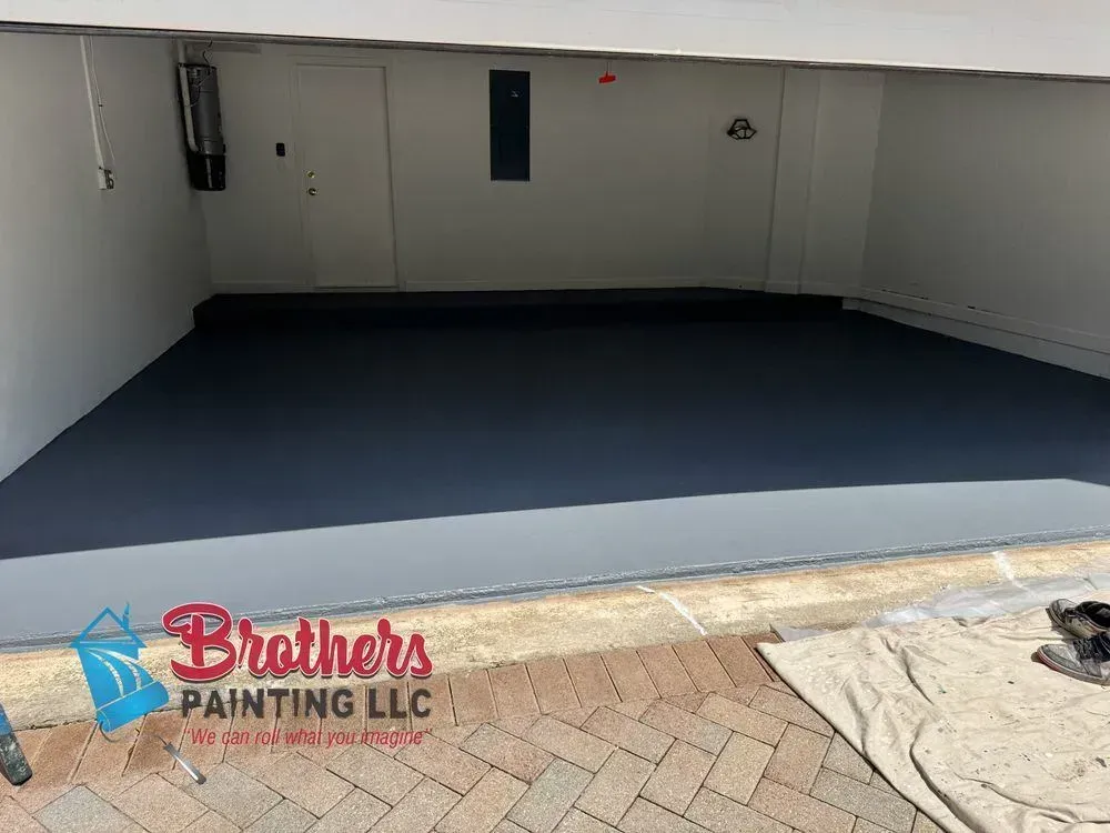 Freshly painted garage interior with dark floor and white walls, viewed from the open doorway