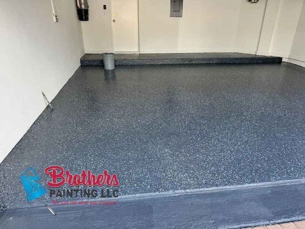 Empty gray epoxy-floored garage with white walls and a small step at the back.