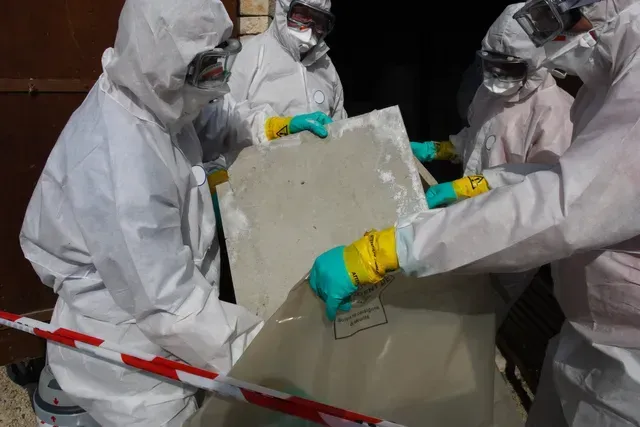 un groupe de personnes en tenue de protection tient un morceau de béton.