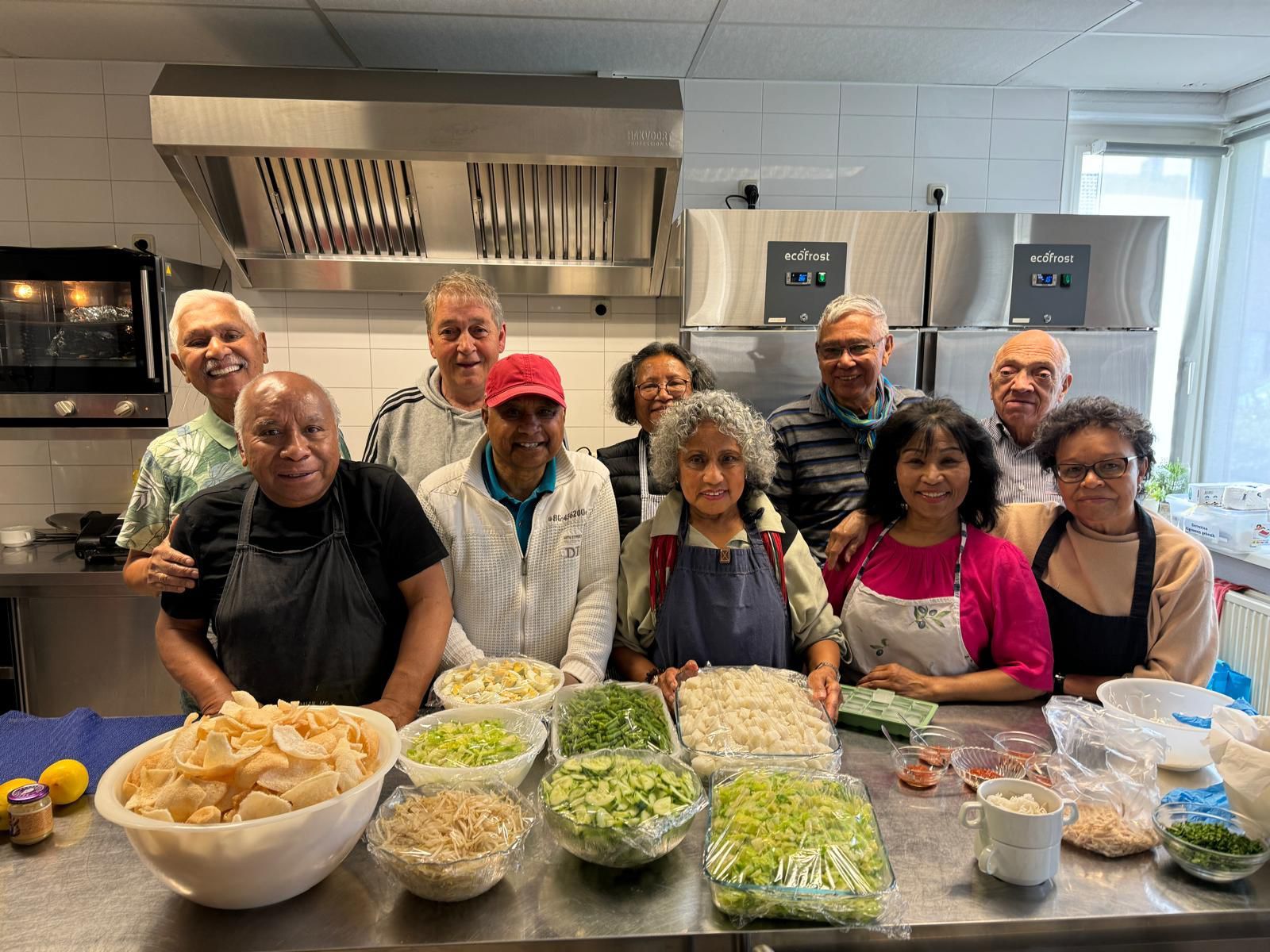 Een groep mensen poseert voor een foto in een keuken.