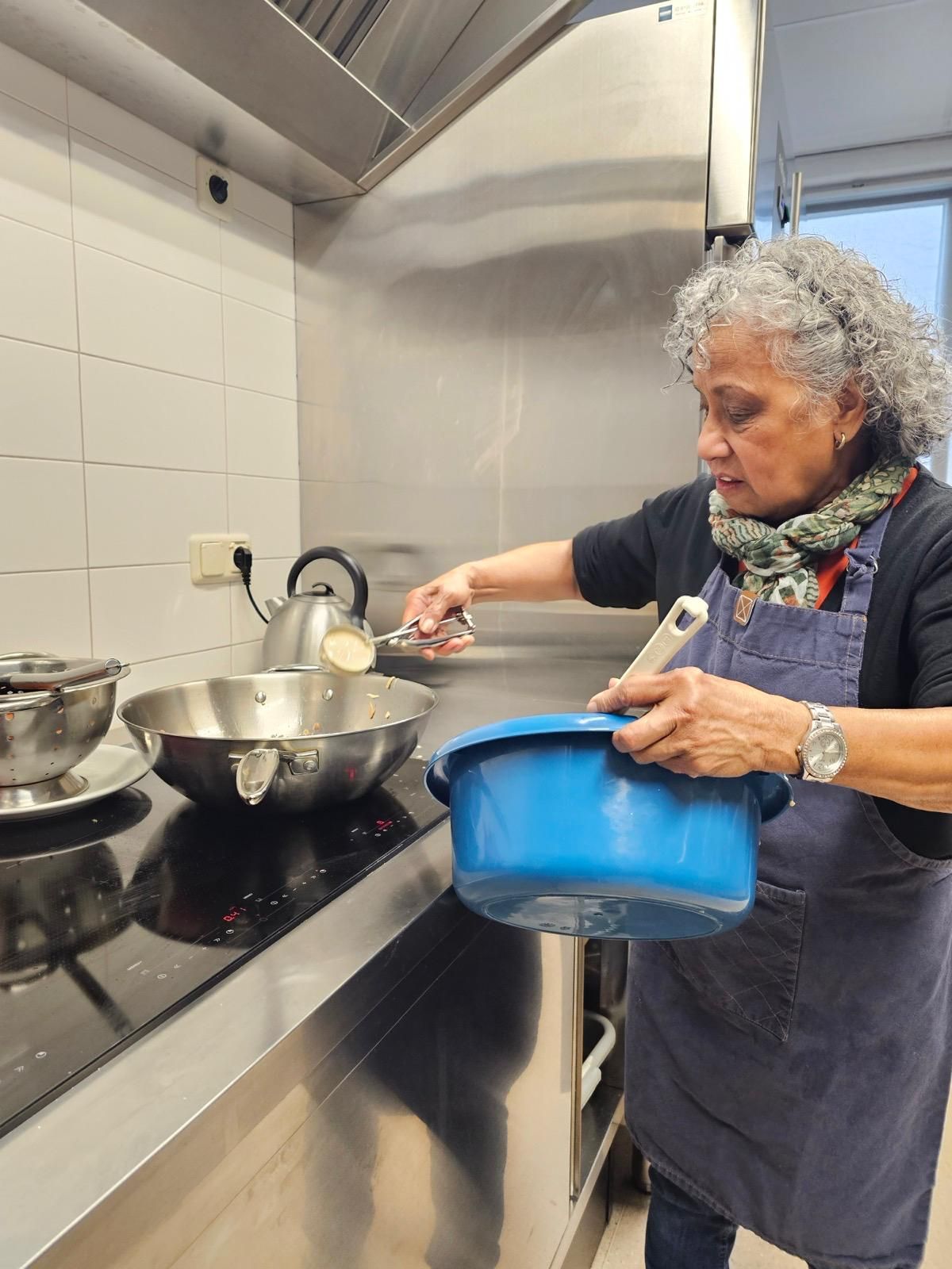 Een vrouw kookt in een keuken terwijl ze een blauwe kom vasthoudt.