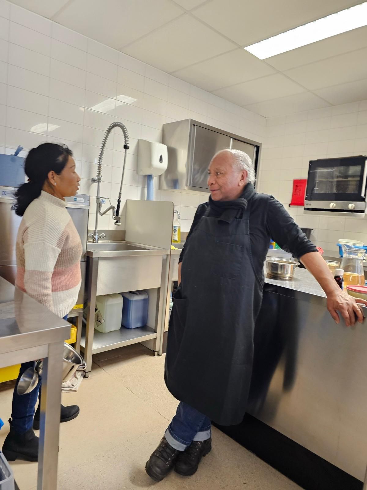 Een man en een vrouw staan ​​in een keuken met elkaar te praten.