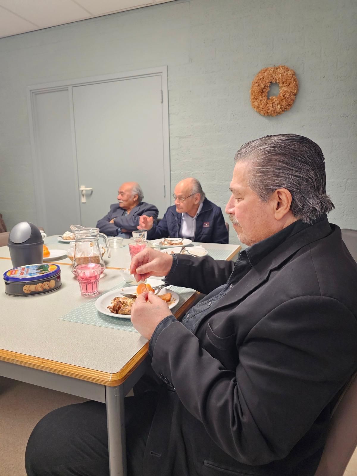 Een man in een pak zit aan een tafel eten.