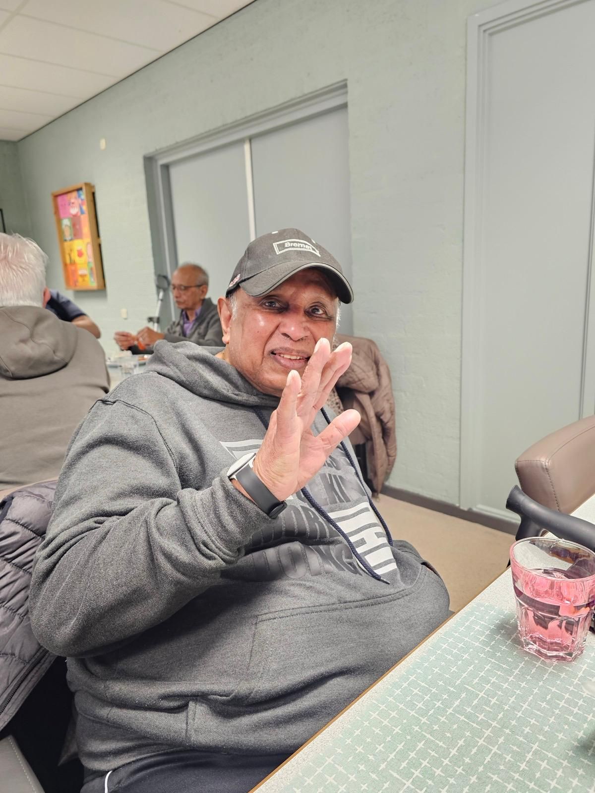 Een man zit aan een tafel met zijn handen in de lucht.