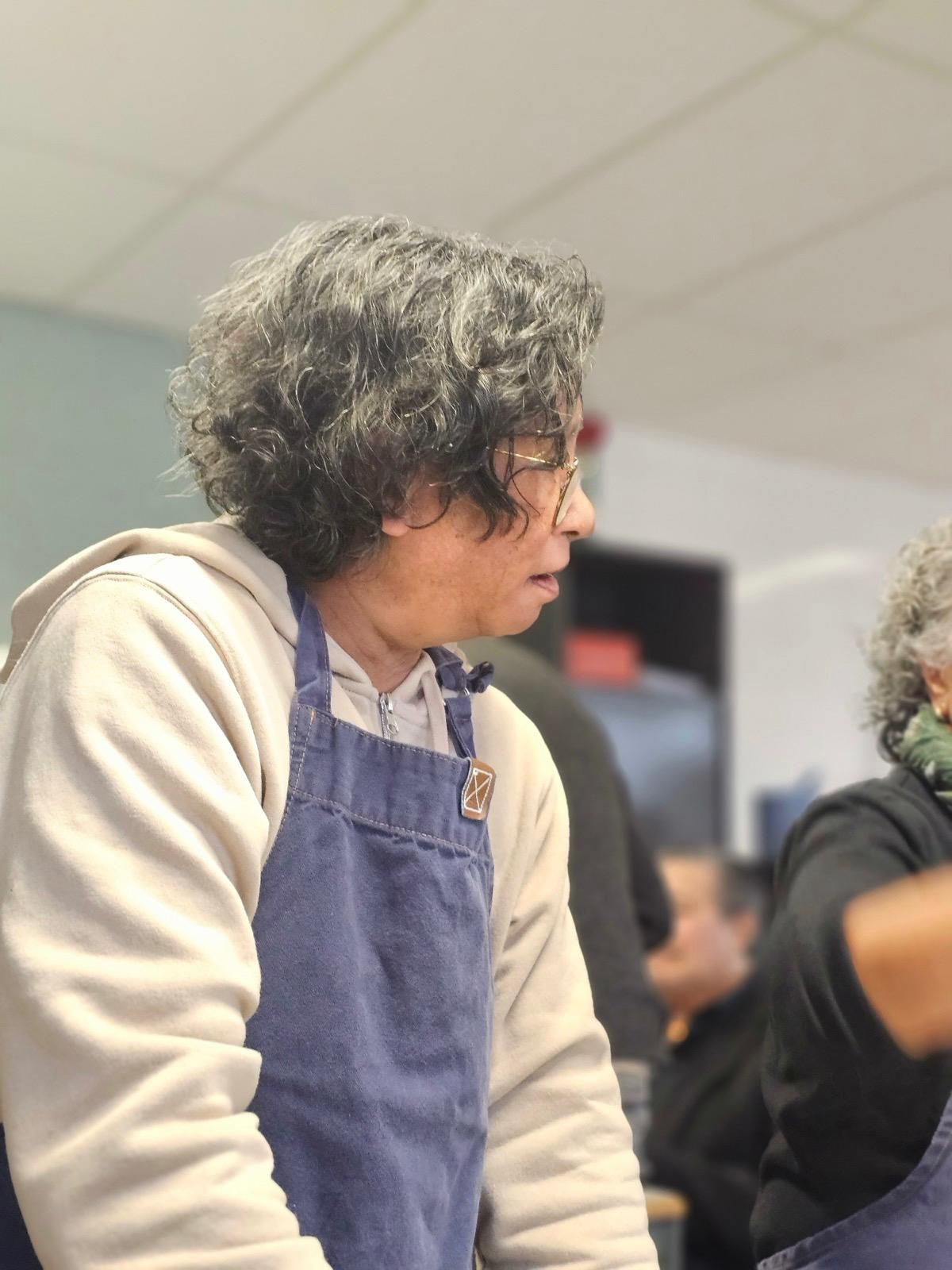 Een man met krullend haar, gekleed in een blauw schort