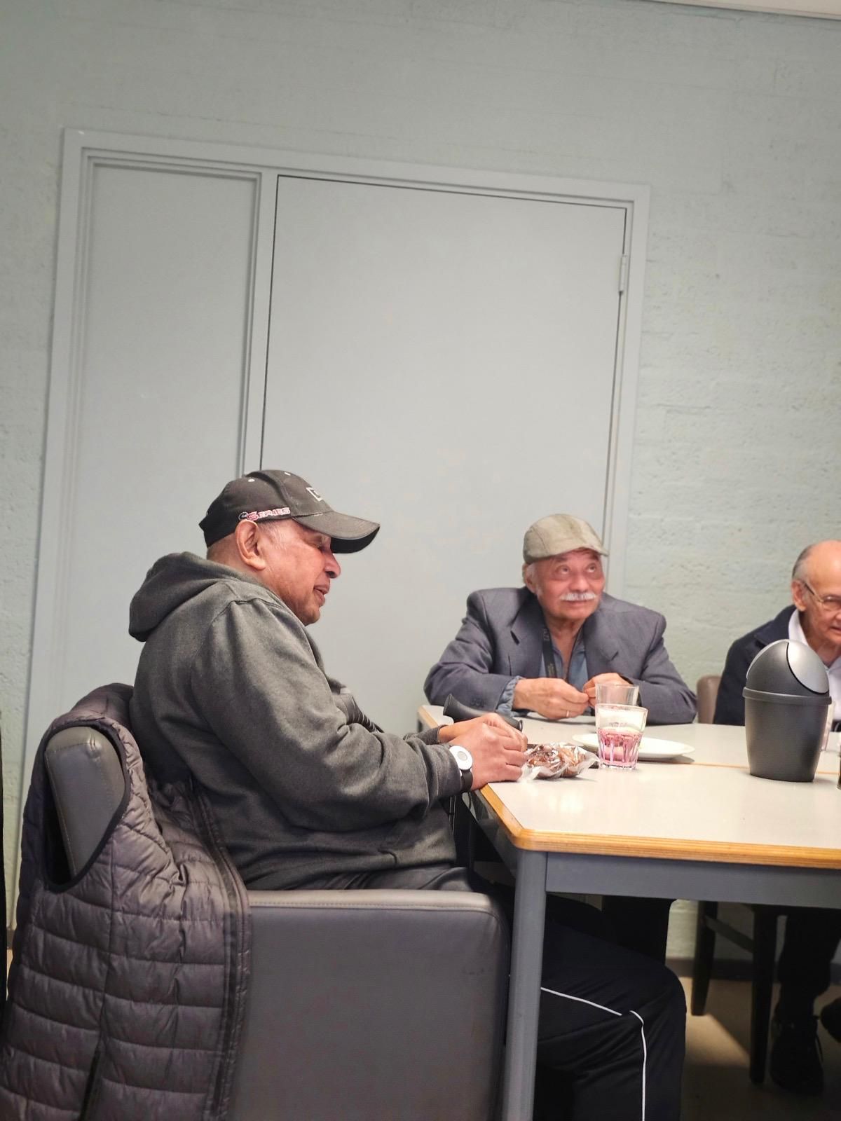 Een groep mannen zit rond een tafel in een kamer