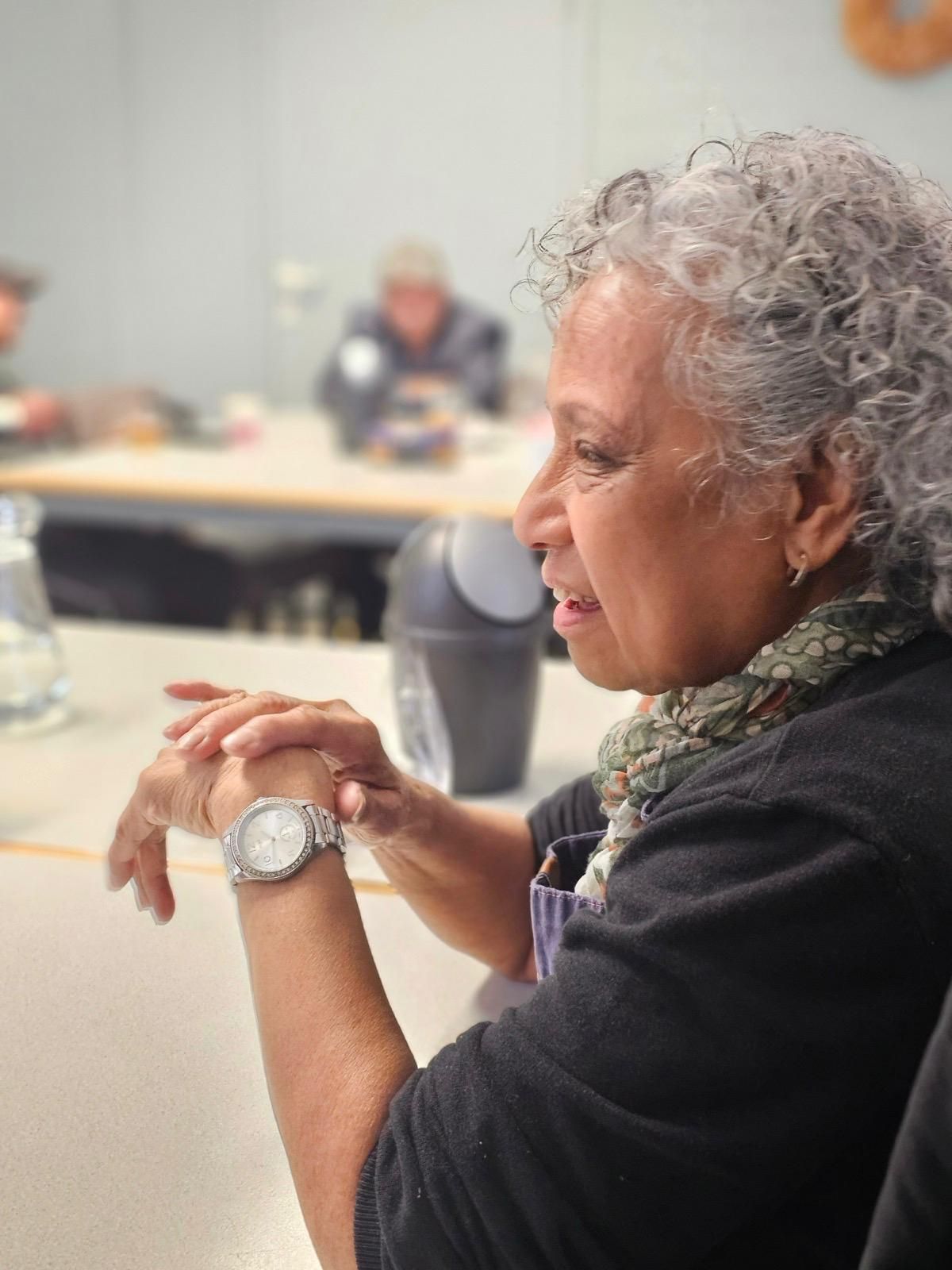 Aan een tafel zit een vrouw met een horloge erop