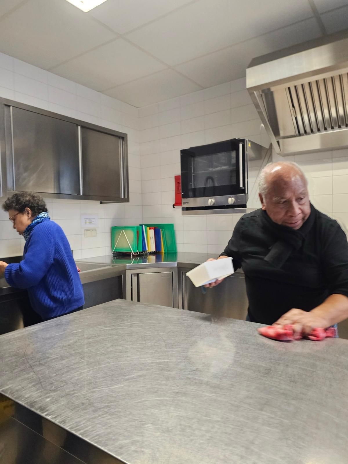 Twee mannen maken een aanrecht in een keuken schoon