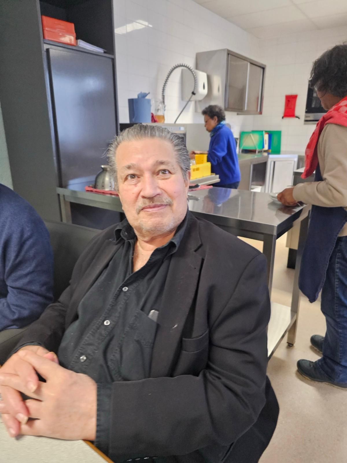 Een man in pak zit aan een tafel in een keuken