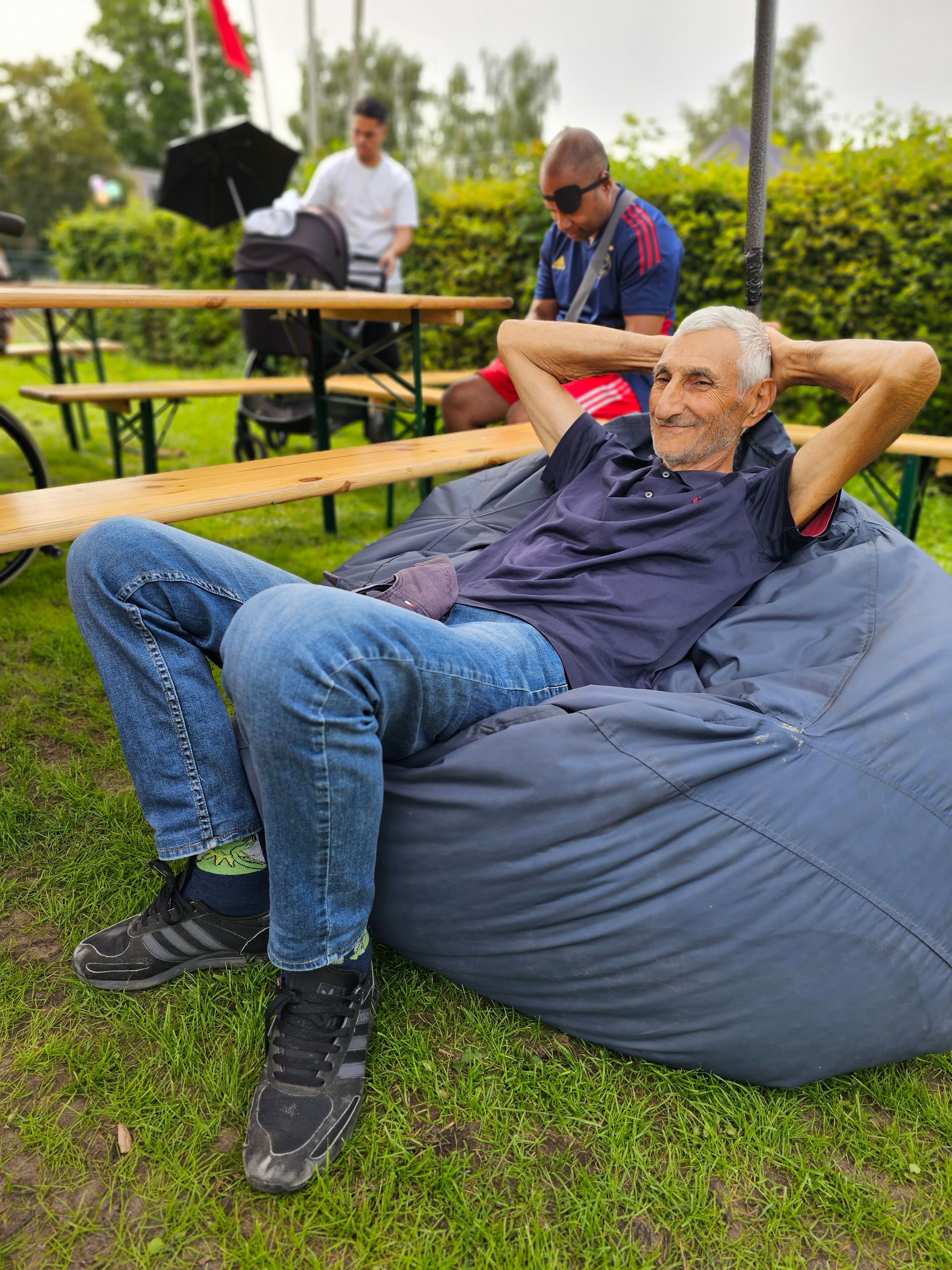 Een man zit op een zitzak in het gras.