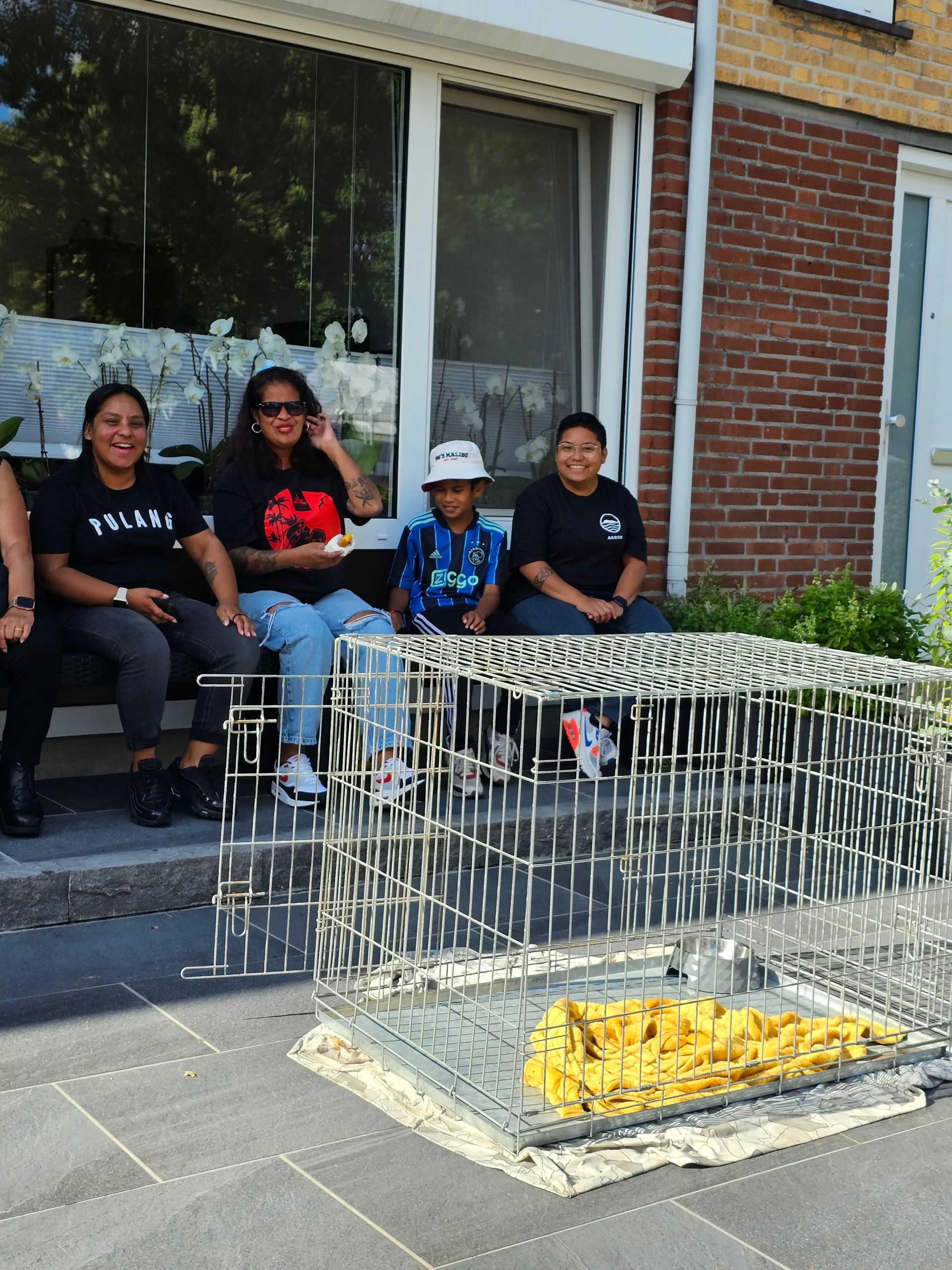 Een groep mensen zit voor een bakstenen gebouw