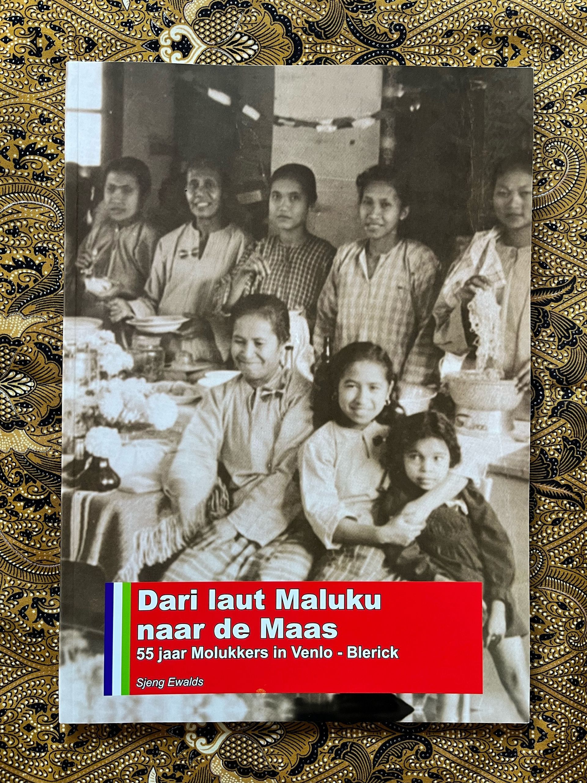 Een zwart-witfoto van een groep mensen die rond een tafel zitten.