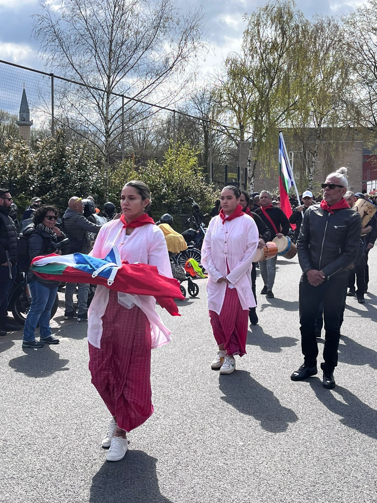 Een groep mensen marcheert door de straat met vlaggen in de hand.