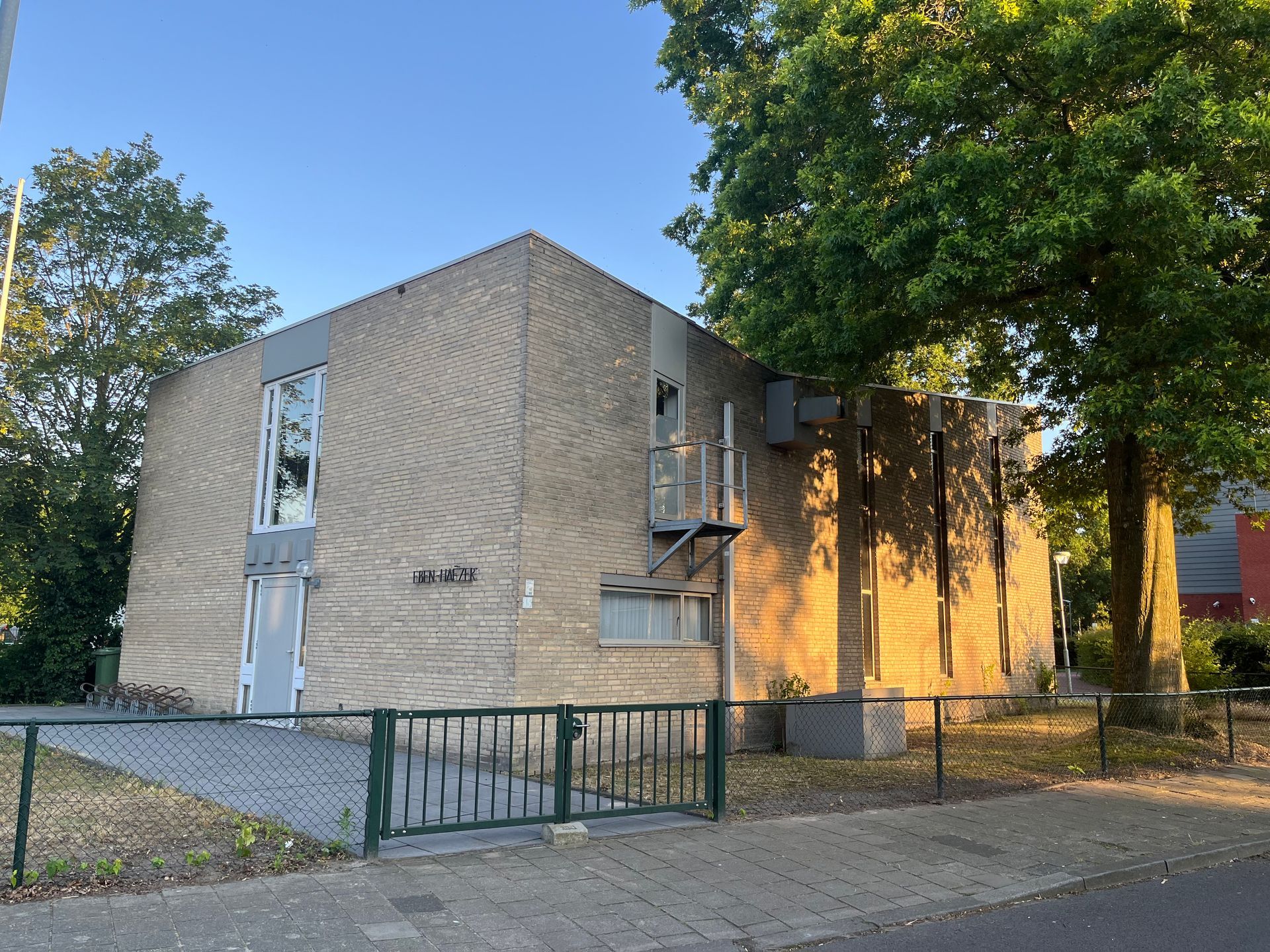 Een groot gebouw met een hek en bomen ervoor