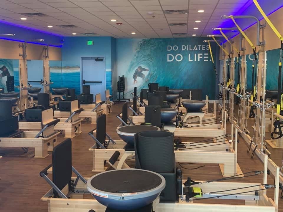 Pilates studio with exercise equipment. Walls have ocean-themed murals.  Blue and neutral color scheme, with exercise apparatus.