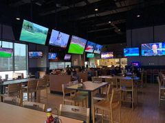 Interior of a Buffalo Wild Wings restaurant, many TVs on walls showing sports, tables and chairs.