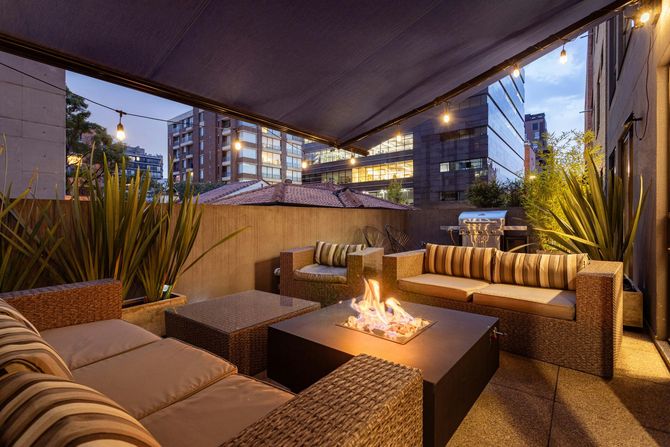 Evening rooftop patio with a fire pit and cozy seating.