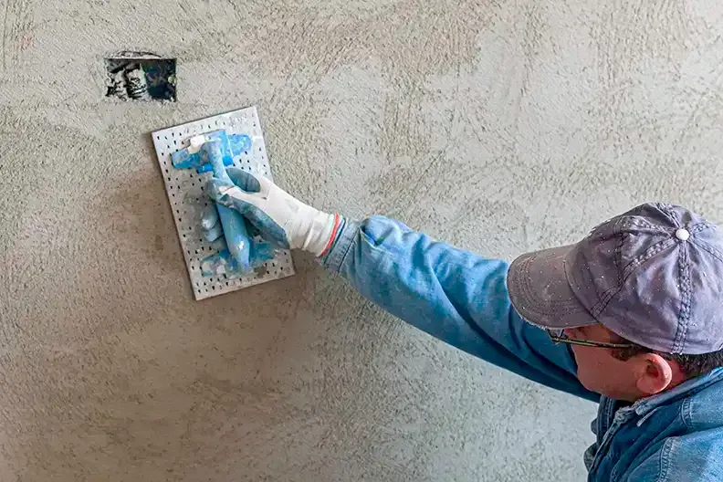 A man is plastering a wall with a trowel.