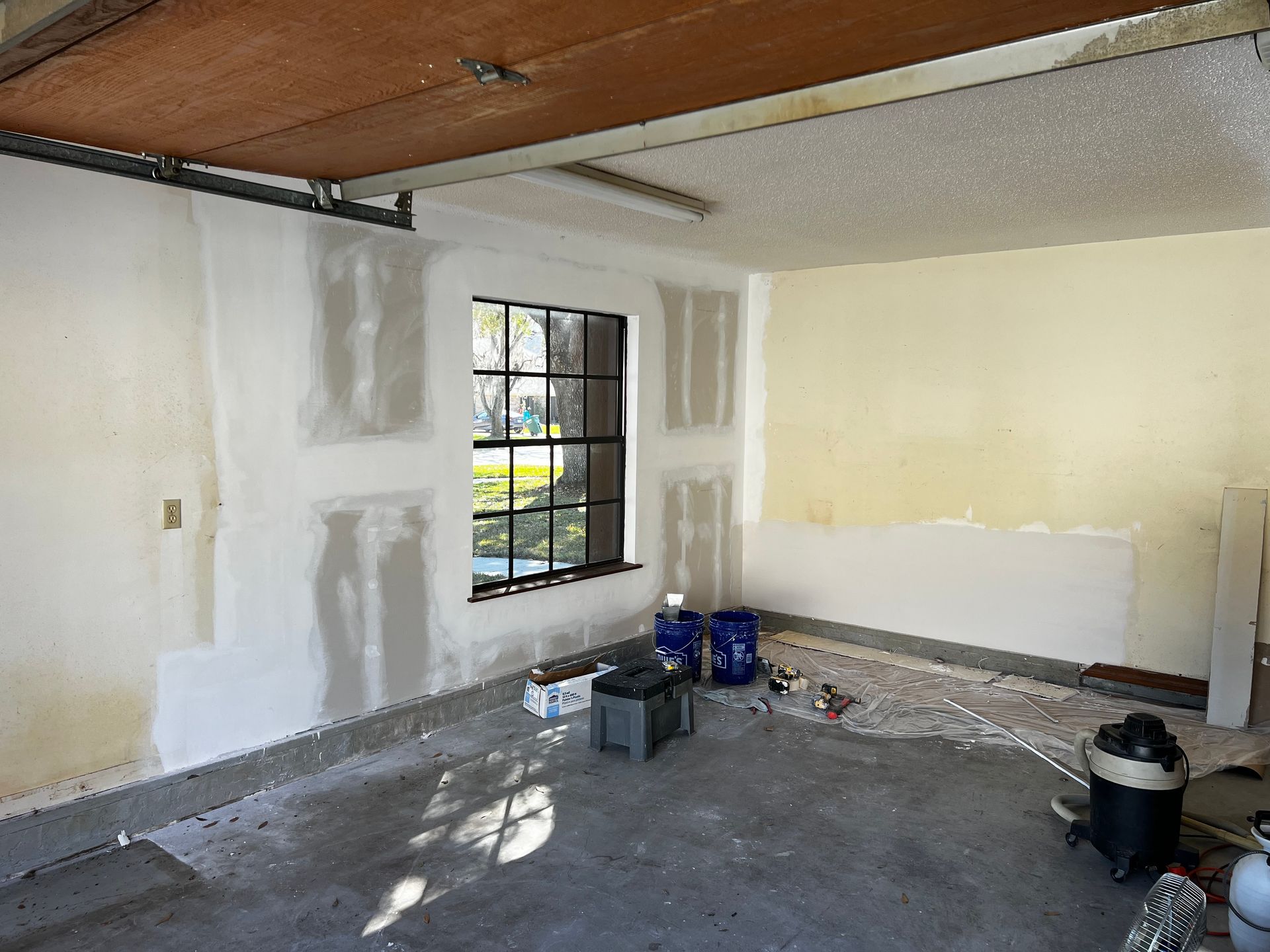 An empty garage with a window and a vacuum cleaner.