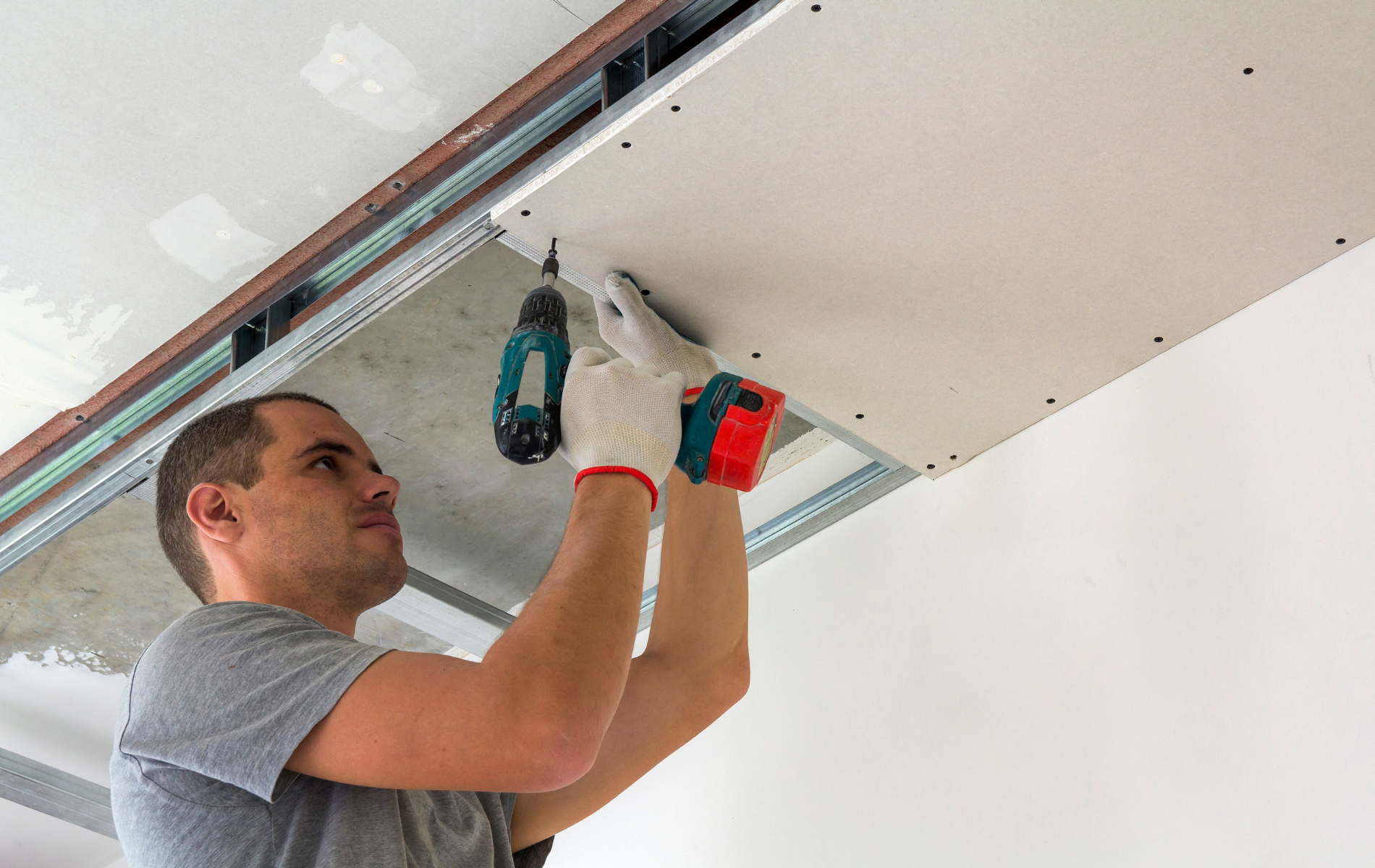 A man is working on a ceiling with a drill.