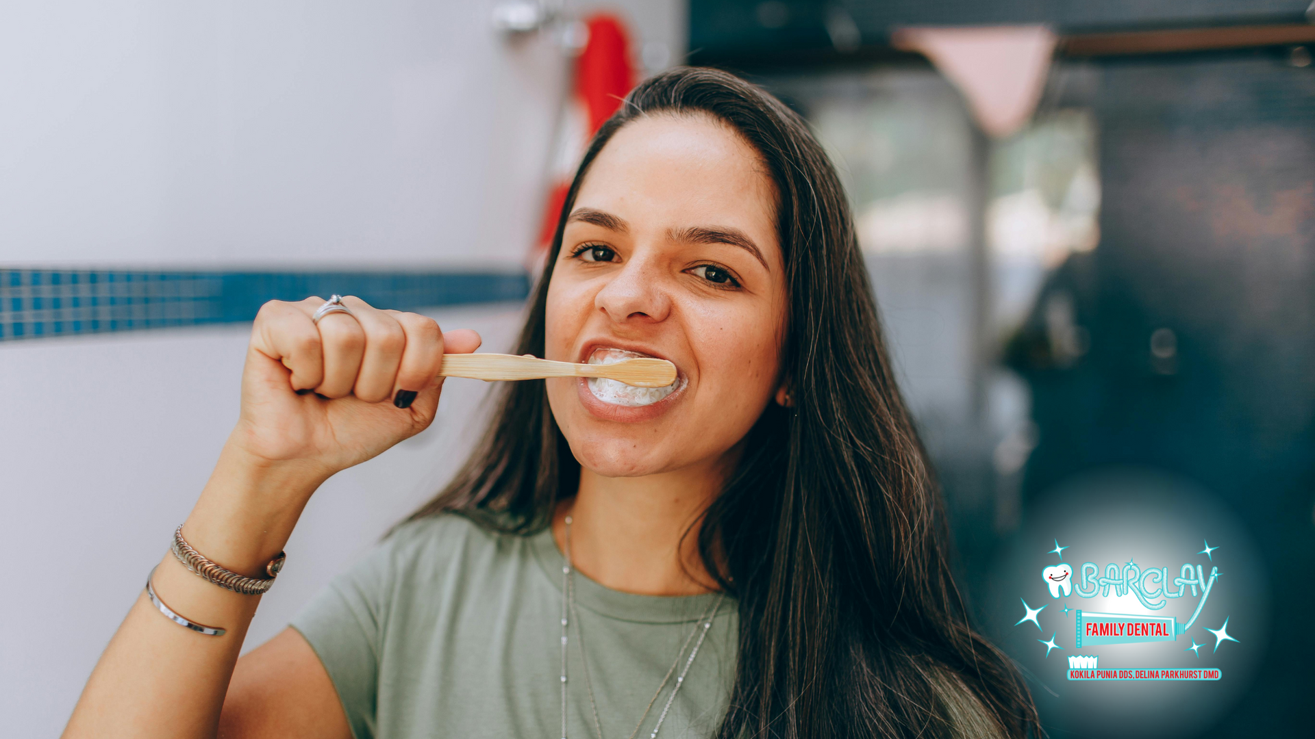 Woman brushing teeth in bathroom. She is smiling. Bamboo toothbrush is used.