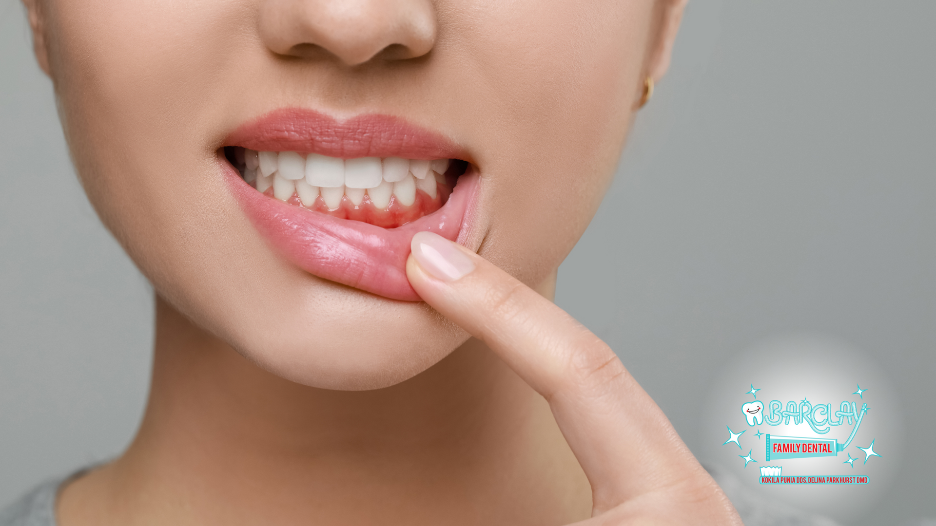 A woman is pointing at her teeth with her finger.