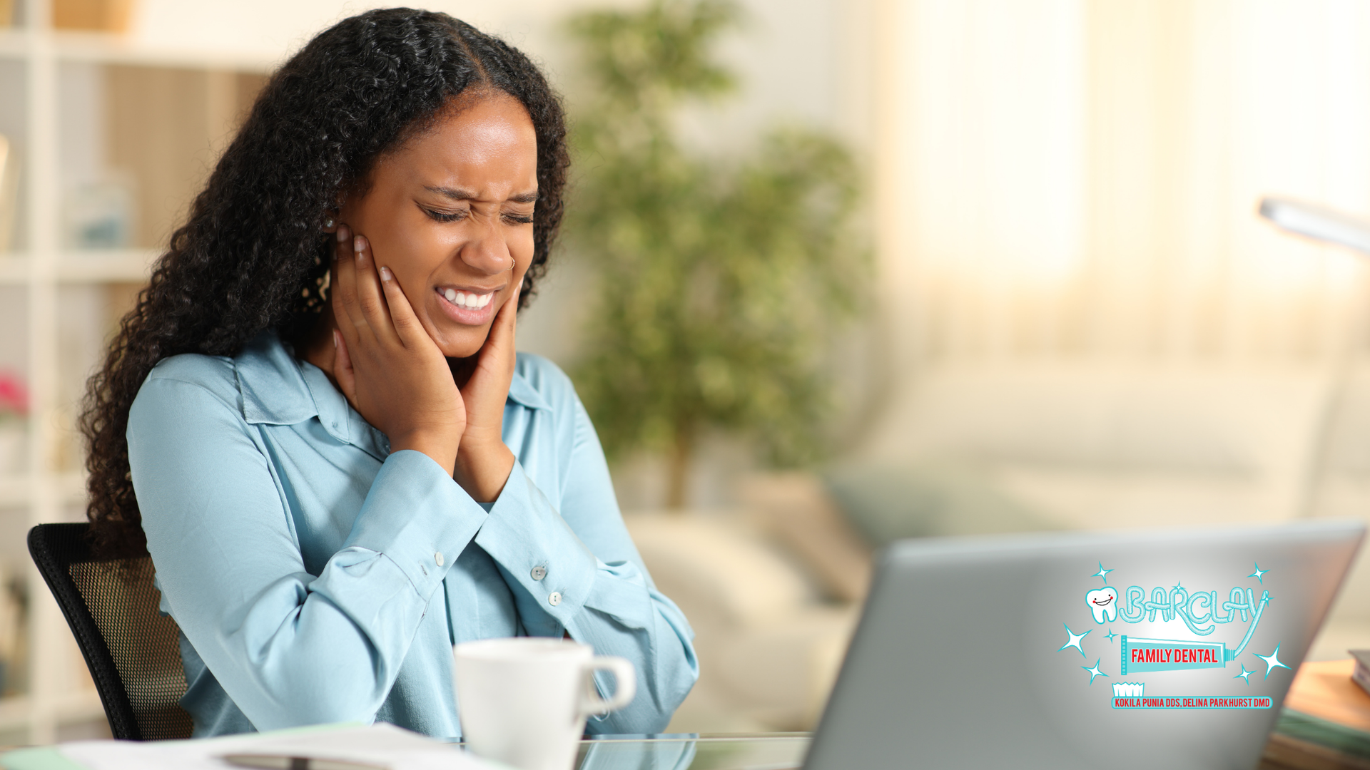 A woman is sitting at a desk with a cup of coffee and a laptop.