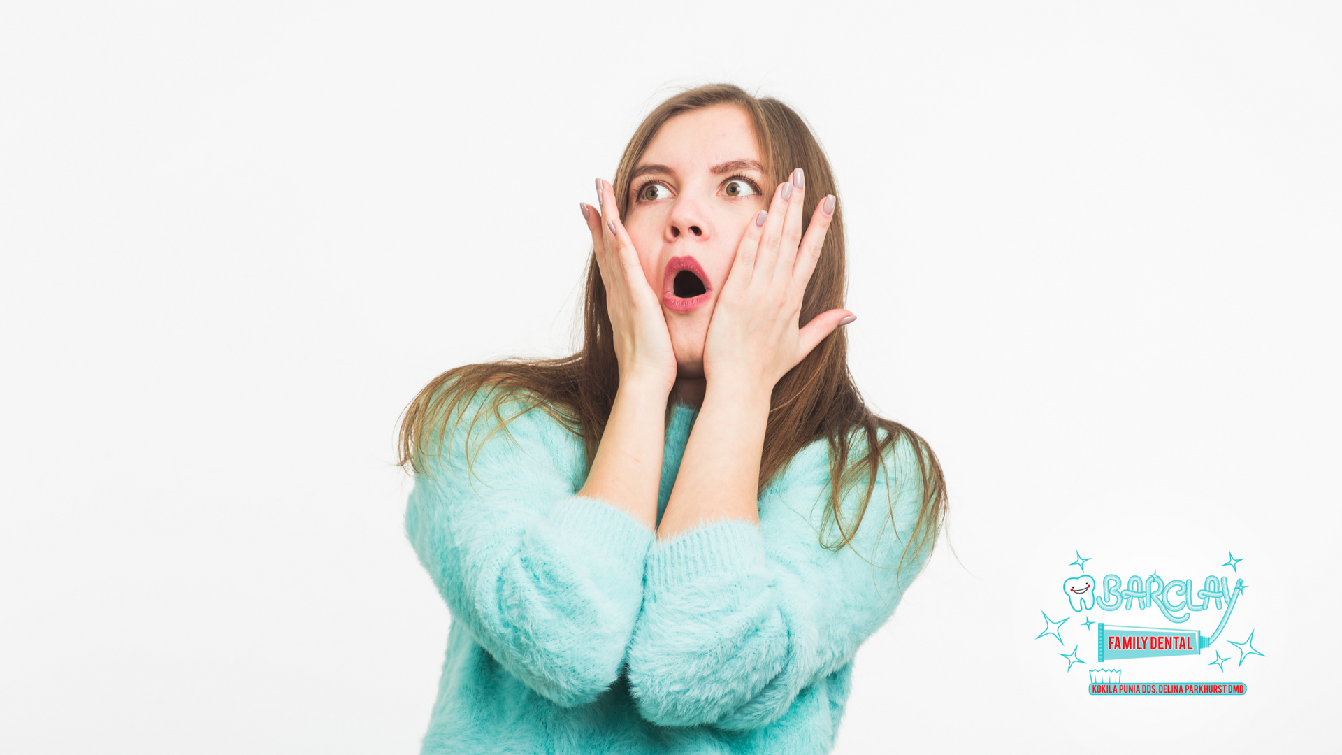 Woman with surprised expression, hands on face, mouth open, wearing blue sweater.