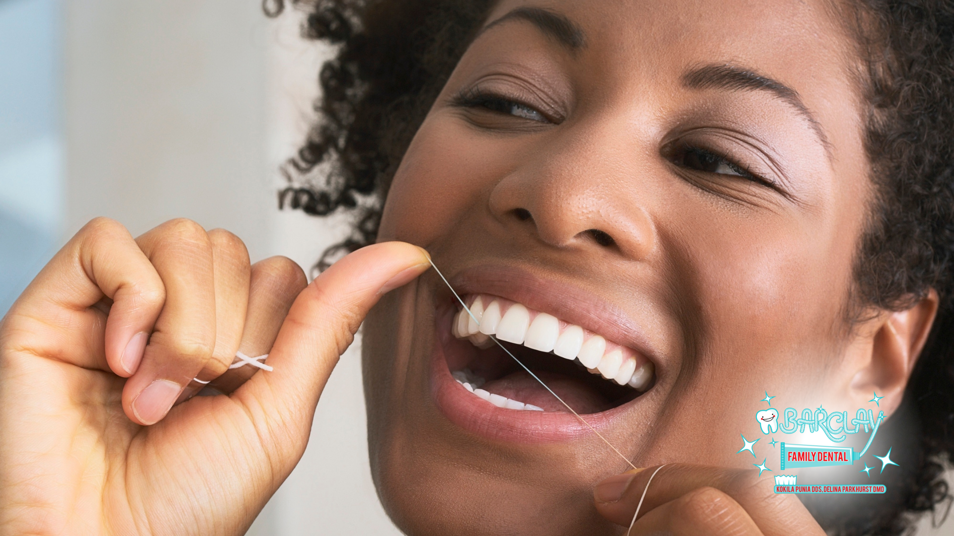 A woman is flossing her teeth with a dental floss.