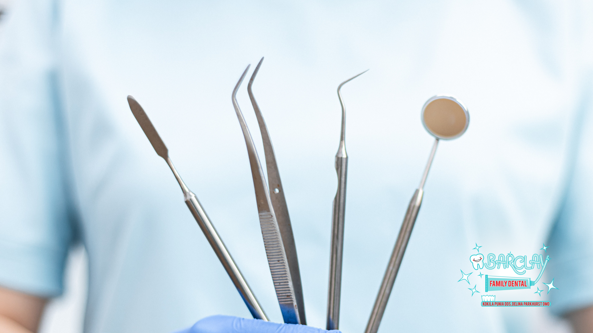 A dentist is holding a bunch of dental instruments in his hand.