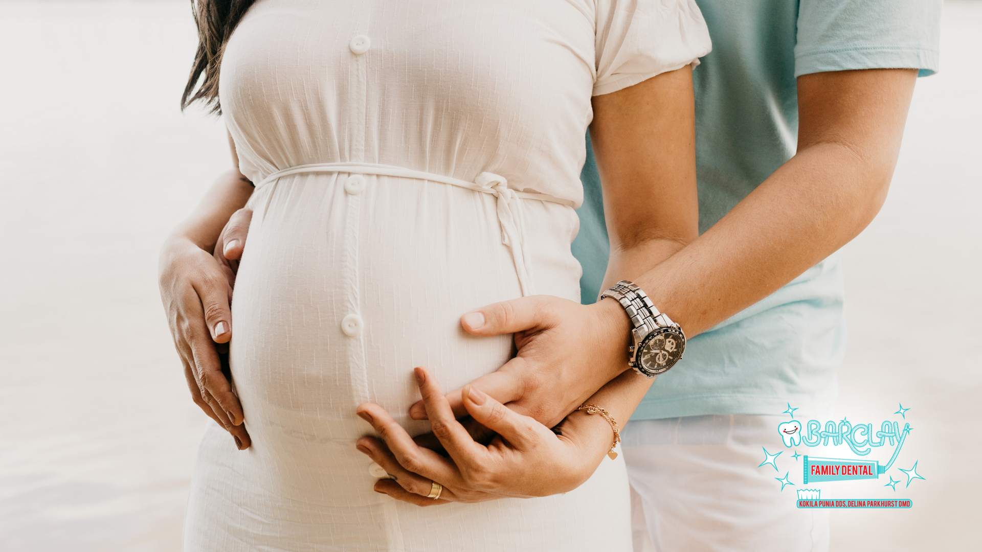 A man and a pregnant woman are holding hands on the beach.