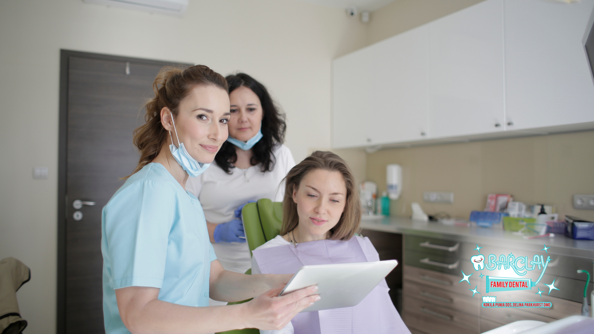 A group of women are standing next to each other in a dental office looking at a tablet.