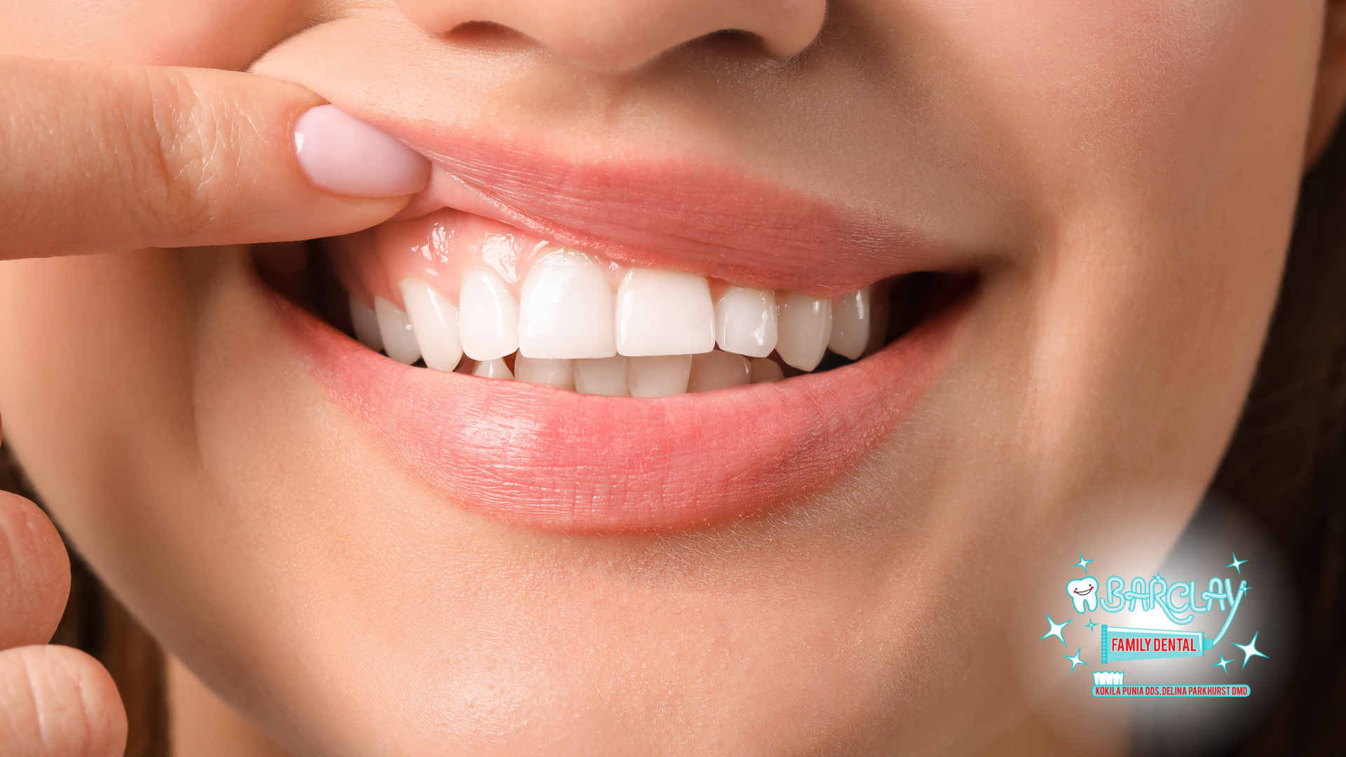 A woman is touching her teeth with her finger.