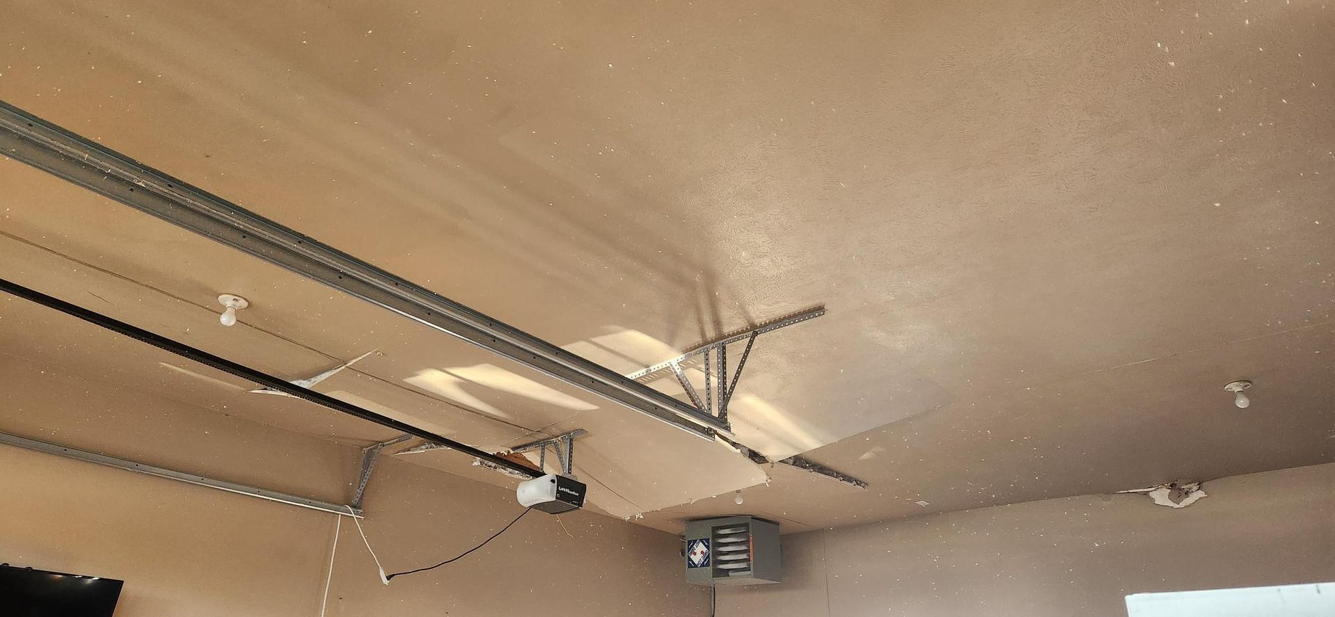 Garage ceiling with a garage door opener and tracks.