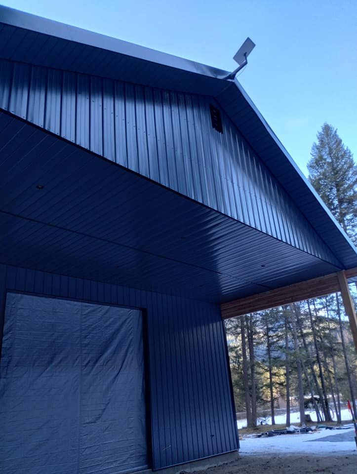 Blue metal building with an attached solar panel and a covered doorway.