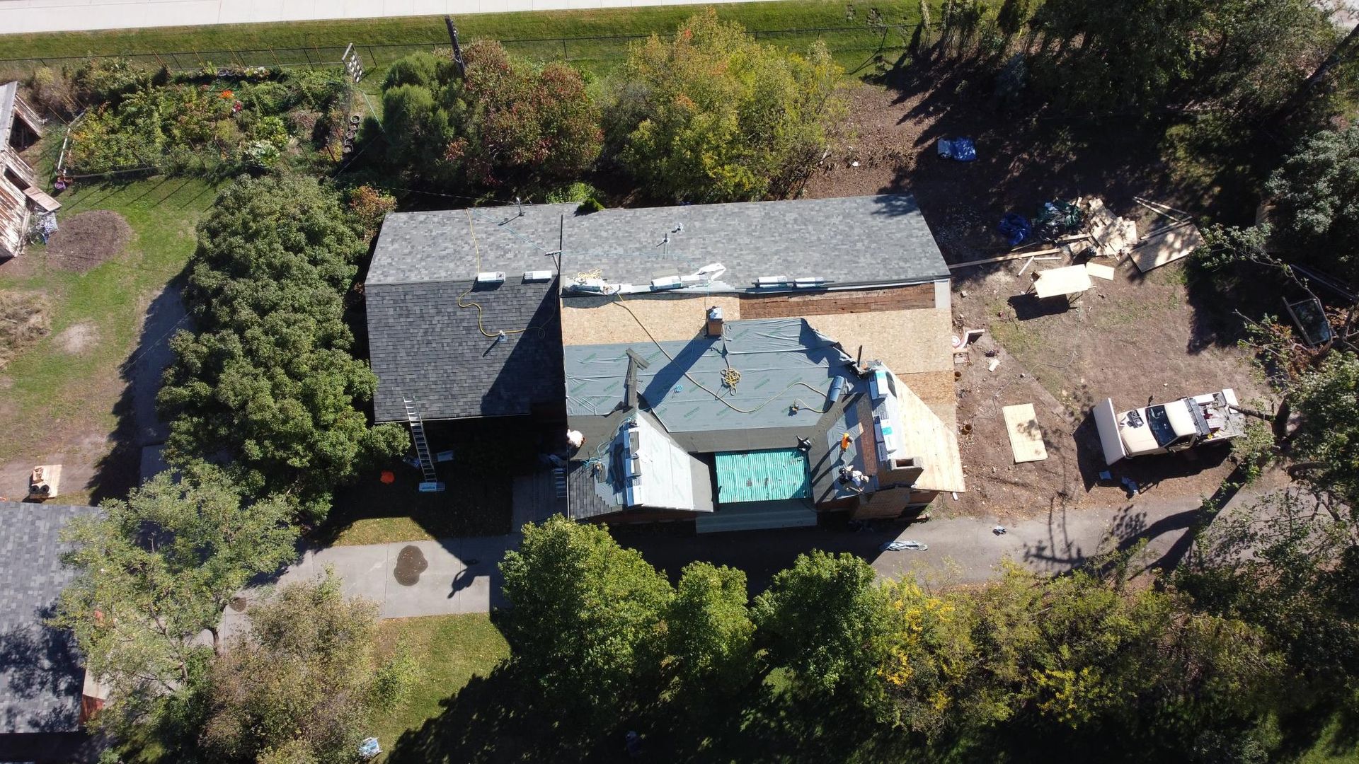 Aerial view of a house with roof partially removed, construction materials nearby.