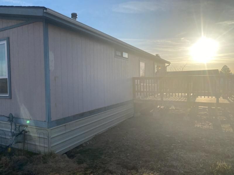 Mobile home with a wooden deck; the sun shines brightly in the background.
