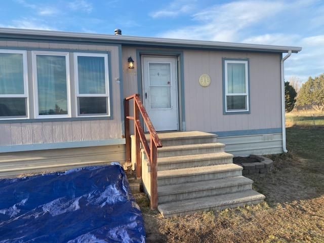 Mobile home with concrete steps and blue tarp on the ground.