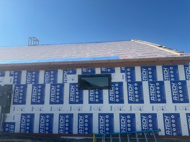 A large modular home being set on foundation by a crane. Construction site with trees in background.