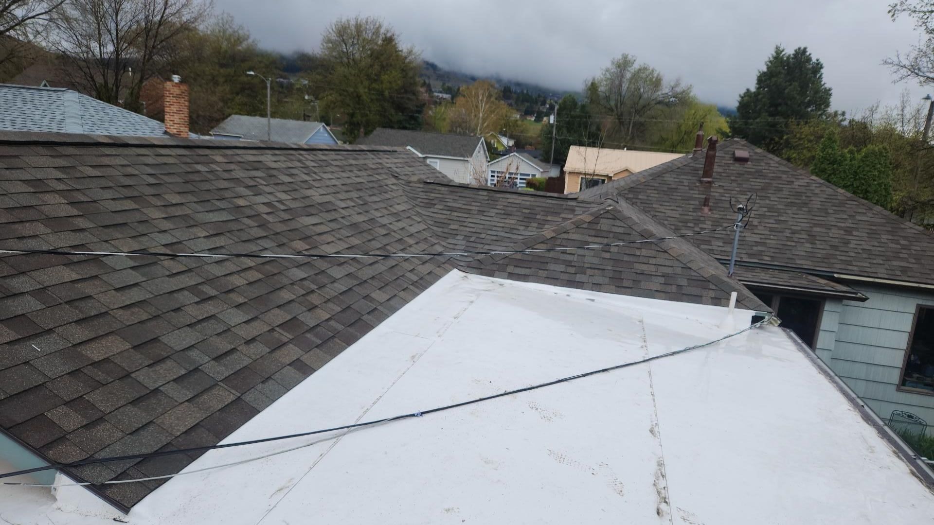Roofs of houses, varying colors and materials, on a cloudy day.