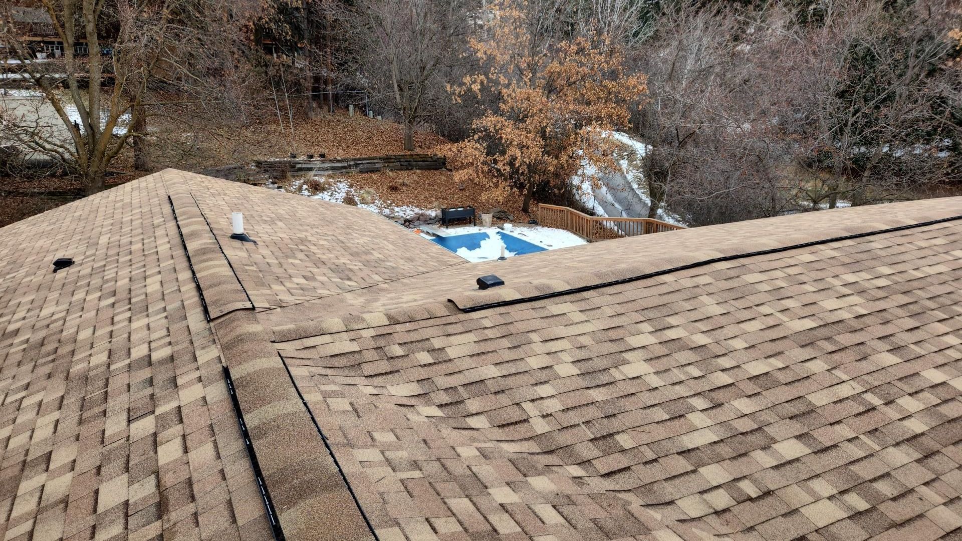 Brown shingled roof with a view of a backyard with a partially covered swimming pool.